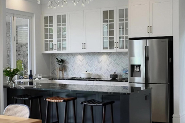 A kitchen with a black island and white cabinets.