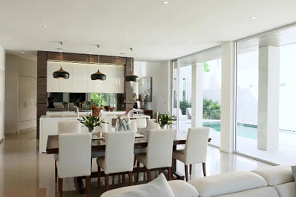 A modern living room with white furniture and large windows, creating a bright and airy space.